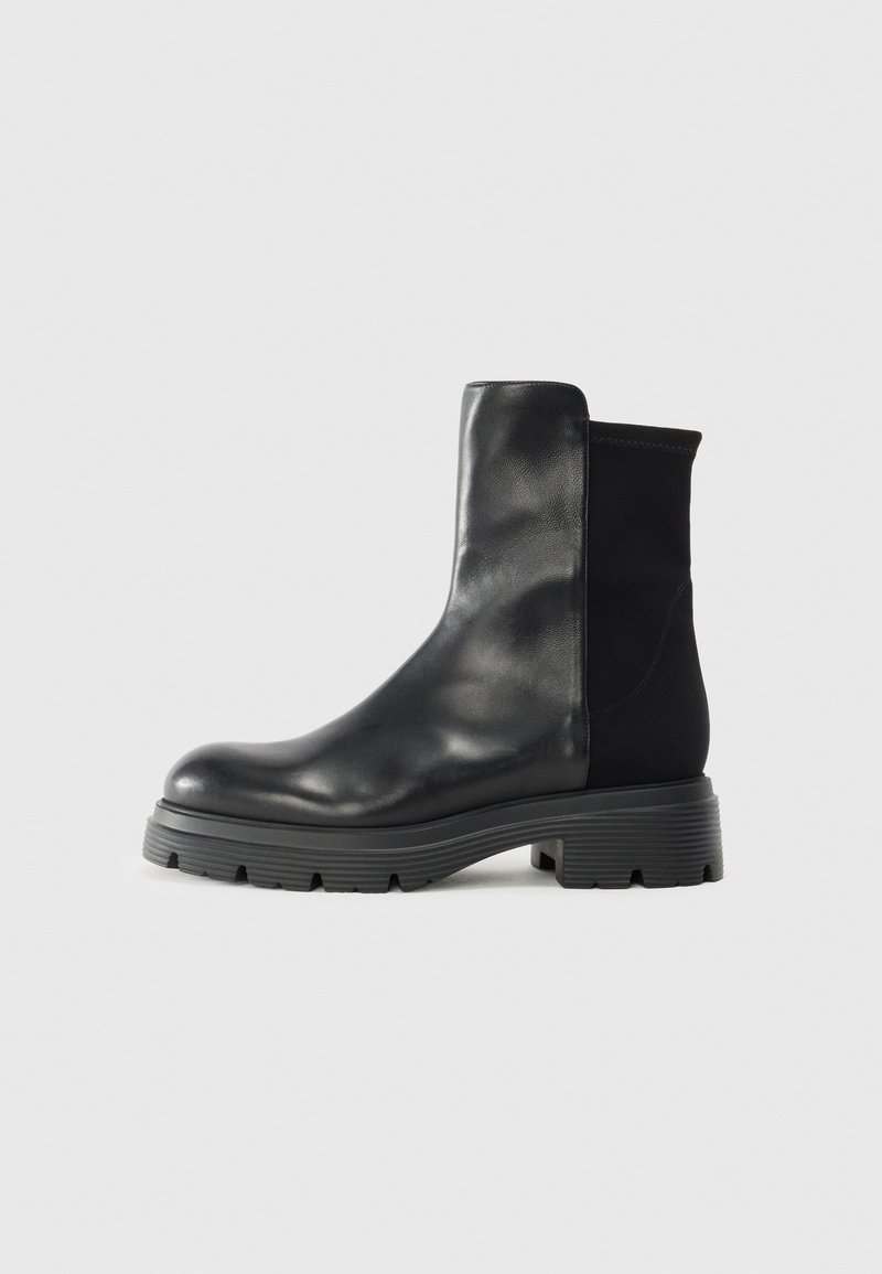Botines negros de tobillo hechos de cuero suave con paneles laterales elásticos, suela de goma gruesa y un diseño elegante y moderno.