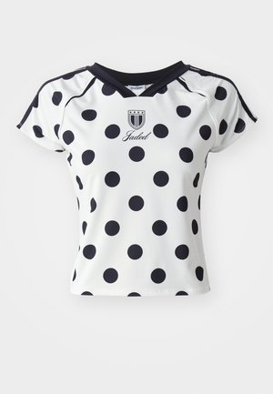 Camisa blanca de manga corta con grandes lunares negros, escote en V y detalle de logo en el pecho, fabricada con un material suave y elástico.