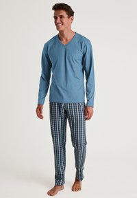 Heren pyjama set met een blauwe lange mouw V-hals top van zachte stof en blauwe geblokte broek met witte accenten. Standaard pasvorm, zonder zakken.