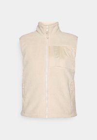 Fleece vesta v svetlo béžovej farbe, s vysokým golierom, predným zipsom a náprsní cestou s hladkou textúrou. Obsahuje dve bočné vrecká.