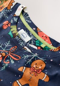 Tengerészkék pamut póló ünnepi motívumokkal, többek között mézeskalács figurákkal és karácsonyfákkal, kerek nyakkivágással és zöld szegéllyel.