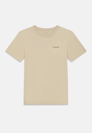 Tricou bej cu mâneci scurte și guler rotund, cu un mic logo „Calvin Klein” pe partea stângă a pieptului, design simplu.