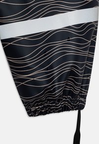 Navy fabric with wave pattern in beige and a silver reflective stripe across the middle. Features an elasticated hem and a drawstring.