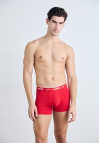 Rote Nike Boxershorts mit einem weißen Logo-Bund, aus elastischem Stoff gefertigt, mit einer figurschmeichelnden Passform und in mittlerer Oberschenkellänge.