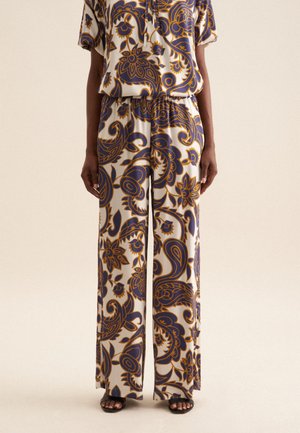 Pantalons larges à motifs avec un design floral en bleu foncé et moutarde sur un fond clair. Fabriqués dans un tissu lisse et léger.