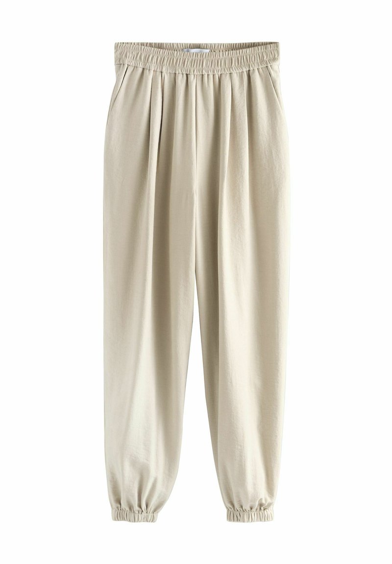 Beige broek gemaakt van zachte stof, met een elastische tailleband, plooien aan de voorkant en elastische boorden bij de enkels.