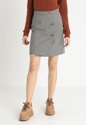Mini-jupe à carreaux avec taille haute, ornée de trois boutons décoratifs sur le devant ; assortie à des baskets chunky marron.