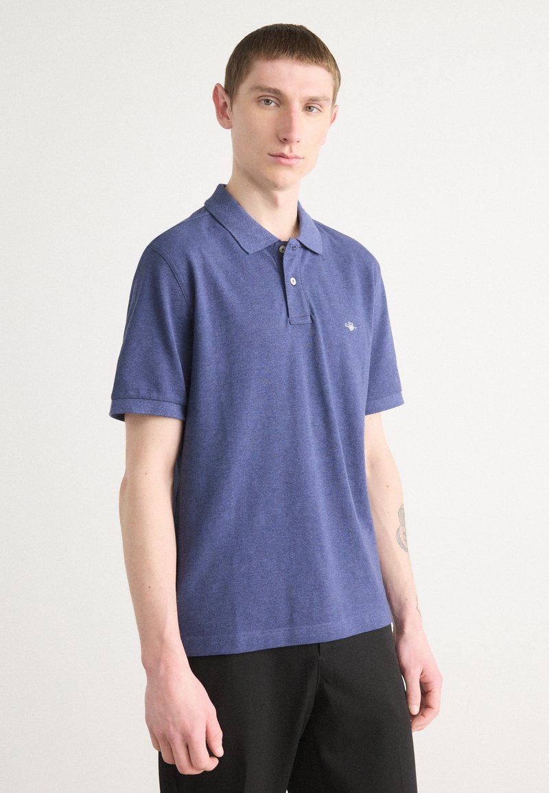 Dunkelblaues Poloshirt mit Kragen, kurzen Ärmeln und einem strukturierten Stoff. Verfügt über ein kleines gesticktes Logo auf der Brust.