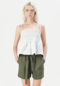 Hvit og lys blå stripete, smocket topp med tynne stropper, parret med olivengrønne, høytlivsshorts med knyttet midje.