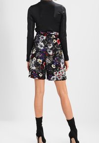 Floral shorts featuring a black background with colorful floral patterns. The waistband is high, and the fabric appears smooth and lightweight.