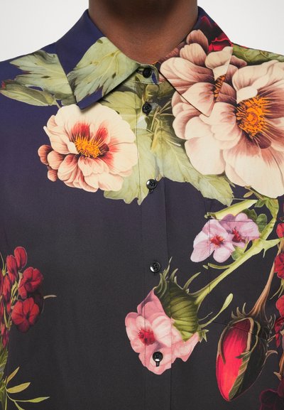 Μπλούζα με φλοράλ σχέδιο σε σκούρο φόντο, διακοσμημένη με μεγάλα λουλούδια σε αποχρώσεις ροζ, κόκκινου και πράσινου, κουμπώνει μπροστά με κλασικό γιακά.