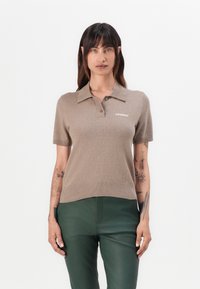Kortermet beige polo genser med ribbestrikket kant, med krage og liten hvit "2ND DAY" logo på brystet. Myk strikket tekstur.