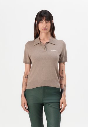 Kortermet beige polo genser med ribbestrikket kant, med krage og liten hvit "2ND DAY" logo på brystet. Myk strikket tekstur.