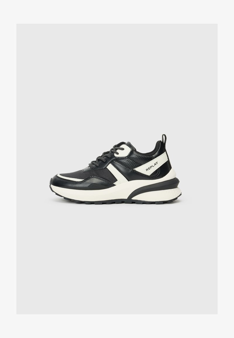 Zwart-witte sneakers met een mix van glad en geperforeerd leer, een dikke zool, ronde neus en contrasterende accenten aan de zijkanten.