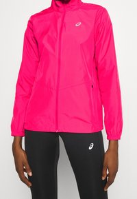 Die rosa leichte Jacke verfügt über einen Reißverschluss vorn, elastische Bündchen und Seitentaschen. Hergestellt aus glattem, wasserabweisendem Material mit Logodetail.