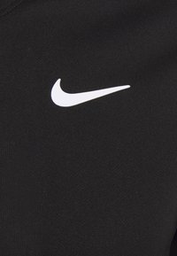 Černá sportovní tkanina s bílým logem Nike ve tvaru swoosh, hladká textura a přiléhavý střih, který se přizpůsobuje tvaru těla.