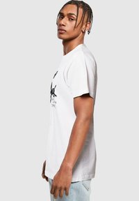Hvid bomulds t-shirt med korte ærmer, med et grafisk print på forsiden. Lige snit, blød tekstur, afslappet design, passende til hverdagsbrug.