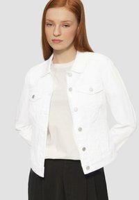 Witte denimjas met zilveren knopen, borstzakken en een klassieke kraag. Gedragen over een lichtgrijs shirt; gladde textuur, getailleerd ontwerp.