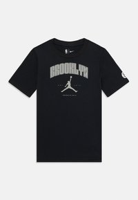 Melna kokvilnas t-kreklu ar apaļu kaklu, kas aizmugurē ir ar "BROOKLYN" un Jumpman grafiku pelēkā krāsā priekšpusē, un nelielu emblēmu uz piedurknes.