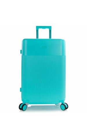 Maleta rígida turquesa con estrías verticales, asa retráctil y cuatro ruedas dobles giratorias.