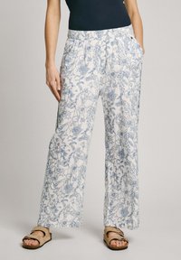 Pantalons blancs à coupe décontractée avec un motif floral bleu, ceinture élastique, poches latérales et texture de tissu douce et légère.