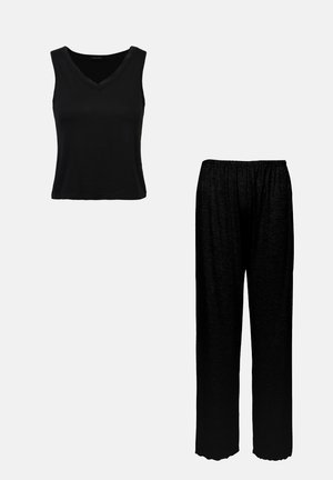 Juodas be rankovių palaidinė su v-formos iškirpte ir nėriniuotu apvadu, derinama su laisvai krentančiomis juodomis kelnėmis su elastine juosta ir tekstūruota medžiaga.