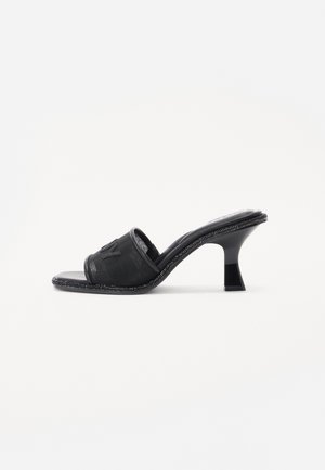 Sort åben-toe mule-sandal med mellemhøj buet hæl og tekstureret rem med diskret præget logo.