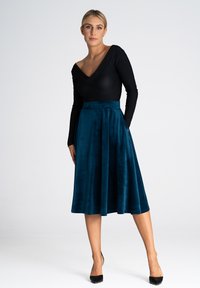 Czarny, długi rękaw top z dekoltem w kształcie litery V, zestawiony z turkusową, aksamitną spódnicą do kolan o dopasowanej talii i zwiewnym kroju.