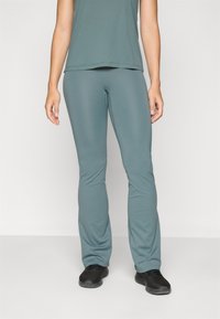 Teal treningsbukser laget av elastisk stoff, med en utsvingt ben-design nær kanten, kombinert med en matchende kortermet topp.