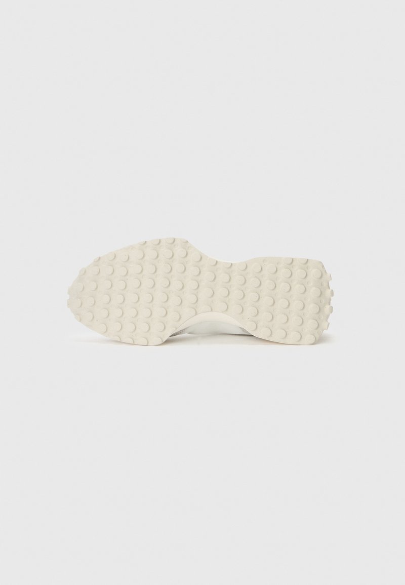 Semelle de sneaker blanche présentant une surface en caoutchouc texturée avec des motifs circulaires pour l'adhérence et la durabilité, forme ergonomique pour le confort.