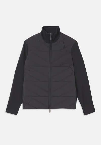 Jachetă hibridă închisă la culoare, cu un front quilted cu model în zig-zag, mâneci lungi netede, guler înalt și închidere cu fermoar.