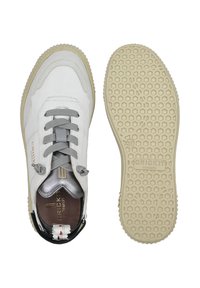 Sneaker bianco in pelle con lacci grigi, accenti metallici e suola in gomma beige texturizzata. Presenta una punta arrotondata e dettagli neri sul tallone.