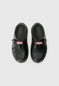 Melni klupi, izgatavoti no sintētiska materiāla, ar priekšējo siksniņu, uz kuras ir sarkans un balts "HUNTER" logo, kā arī ventilācijas atveres sānos.