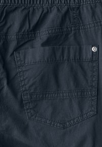 Shorts légers bleu marine avec une taille élastique, dotés d'une poche arrière cousue et d'une couture de bouton en métal. Texture lisse.