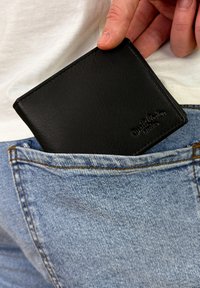 Portafoglio in pelle nera parzialmente visibile in una tasca posteriore di jeans blu, caratterizzato da una texture liscia e un marchio in rilievo.