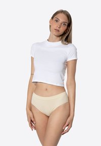 T-shirt blanc court en coton, associé à un slip seamless beige clair. Texture lisse, design ajusté et col rond.