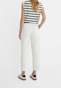 Witte tailored pants met een rechte snit en een voorvouw, gecombineerd met een navy gestreepte short-sleeve top en witte sneakers met zwarte accenten.