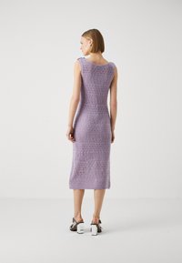 Abito lavorato a maglia viola lavanda di lunghezza al ginocchio con schiena scoperta e un motivo testurizzato. Presenta un colletto rotondo e una silhouette aderente.
