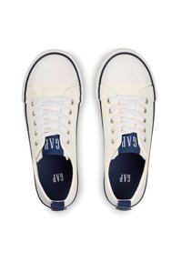 Witte canvas sneakers met marineblauwe accenten. Kenmerken zijn een ronde neus, witte veters en een gestructureerd oppervlak. Merken zichtbaar op de binnenzool.