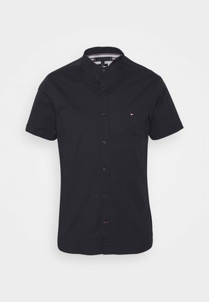 Zwart overhemd met korte mouwen en knopen, mandarijnkraag en een klein rood, wit en blauw logo op de linkerborst.