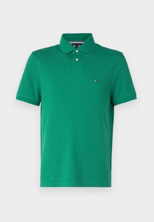 Žalias medvilninis polo marškinėlis su apykakle, dviem mygtukais priekyje ir maža logotipo etikete ant krūtinės. Trumpomis rankovėmis ir klasikiniu siluetu.