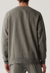 Szary polarowy sweter z długimi rękawami, okrągłym dekoltem, ściągaczami przy rękawach i u dołu. Charakteryzuje się gładką fakturą i luźnym krojem.