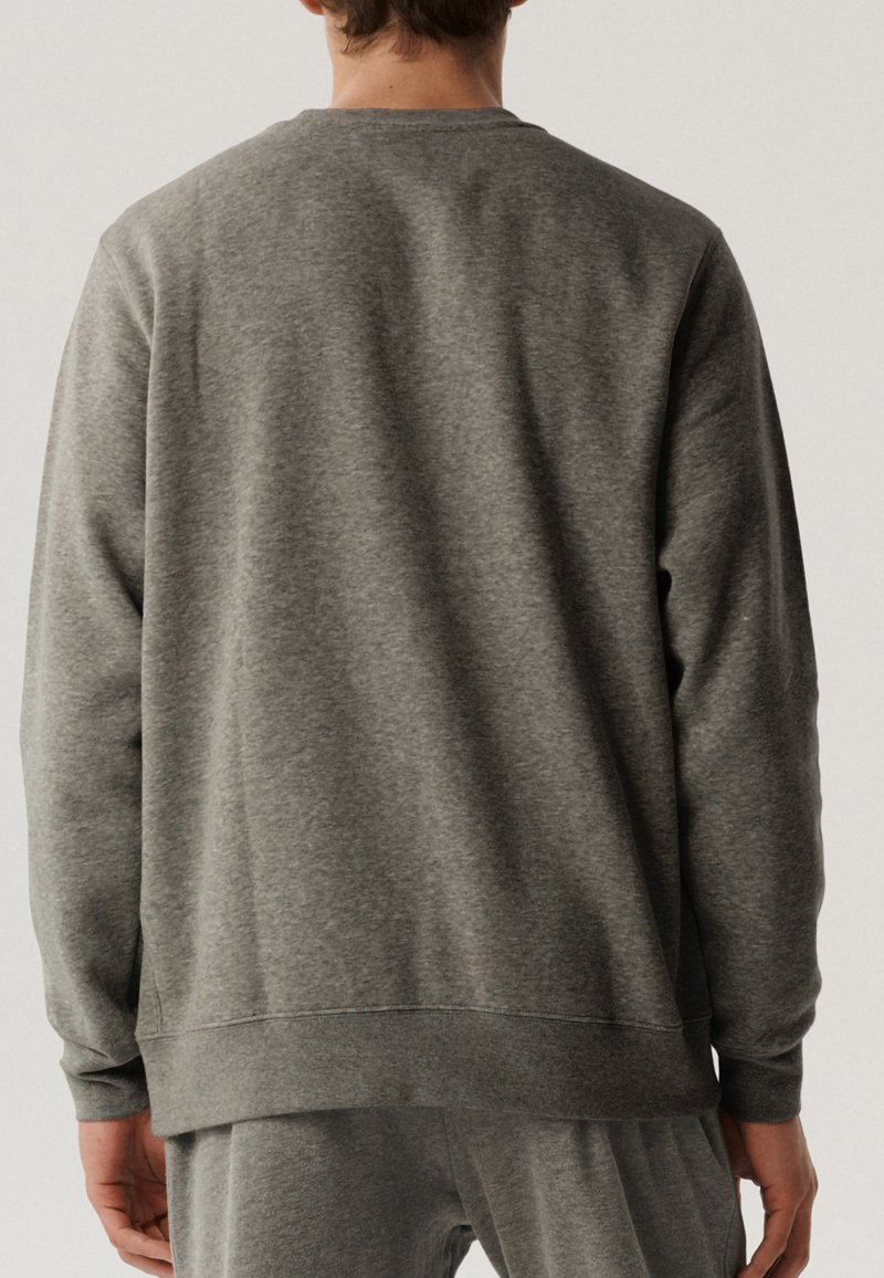 Szary polarowy sweter z długimi rękawami, okrągłym dekoltem, ściągaczami przy rękawach i u dołu. Charakteryzuje się gładką fakturą i luźnym krojem.