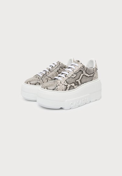 Chaussures style sneaker avec semelles épaisses blanches à plateforme et empeignes gris motifs peau de serpent avec lacets blancs sur un fond uni.