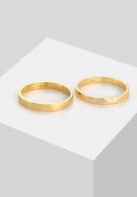 Gold rings made of 925 silver, one smooth and polished, the other with a textured, brushed finish. Both feature minimalist design.