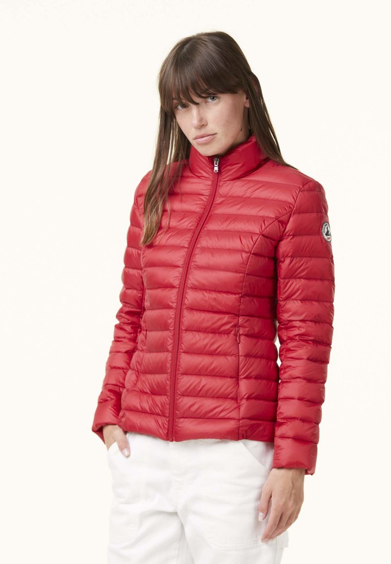 Giacca imbottita rossa con colletto alto, trapuntatura orizzontale e chiusura frontale con zip. Presenta una patch con logo sulla manica sinistra. Texture liscia.