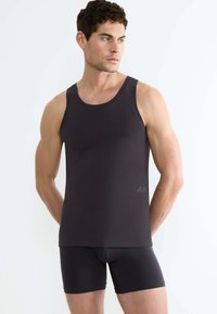 Canotta grigia scura realizzata in tessuto morbido e elastico, con un classico collo rotondo e una vestibilità slim. Abbinata a slip boxer coordinati.