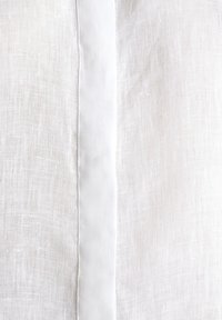 Tissu en lin blanc avec une bande verticale opaque blanche cousue au centre, montrant une texture fine et des détails de couture.