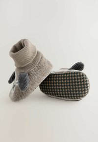 Grau gestrickte Stiefelchen mit umgeschlagenem Kragen, versehen mit einem Hunde-Gesicht und Ohren. Strukturierte Sohle mit Hahnentrittmuster. Weiches Material.