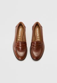 Mocassins en cuir marron avec un détail de bride tressée, bout arrondi et semelle texturée. Finition lisse avec une surpiqûre contrastante autour du bord.